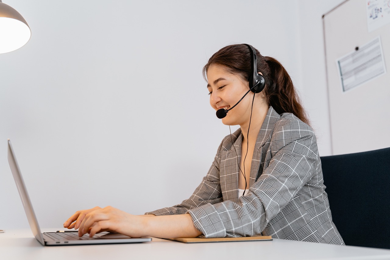 Kundenservice-Agent mit Headset bei der Arbeit am Laptop